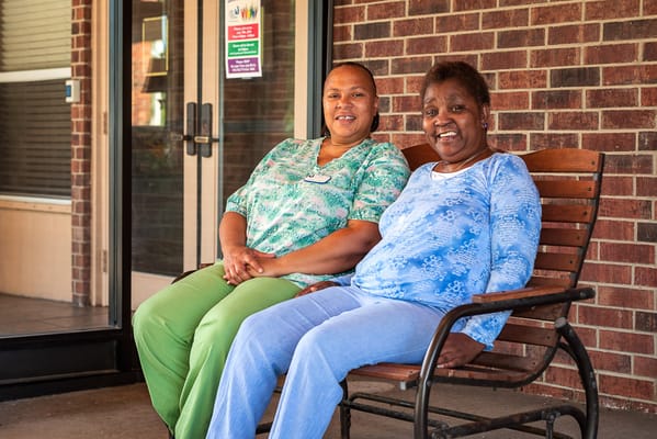 Two women sitting on a bench outside the facility