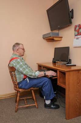 Resident using a computer at a desk in a private room