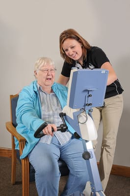 A caregiver assisting a resident with an exercise machine
