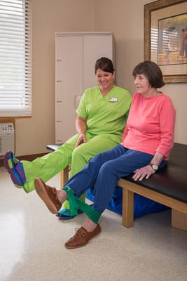 Therapist assisting resident with exercises in a bright room