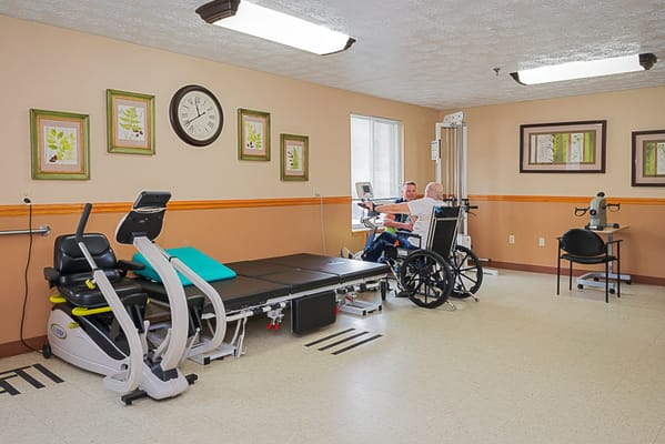 Therapy room with a resident and staff member engaged in exercises