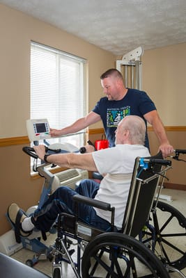 A staff member assisting a resident with exercise equipment