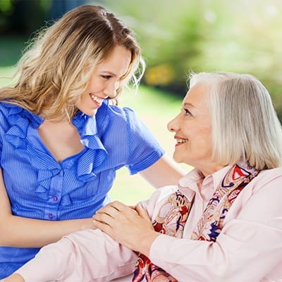 A caregiver smiling with a senior resident outdoors