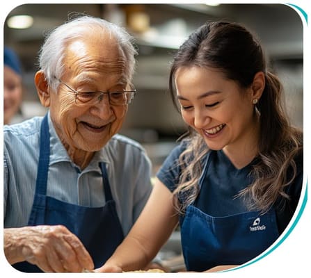 Senior resident and staff member cooking together in the kitchen