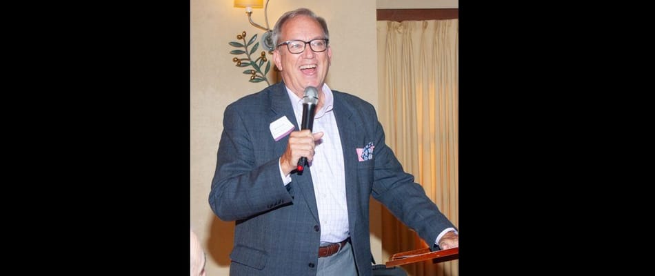A man speaking at an event in an indoor setting