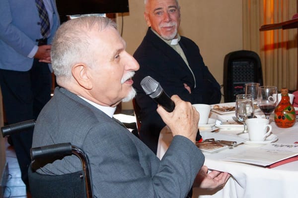Resident speaking during a gathering with staff in a dining setting
