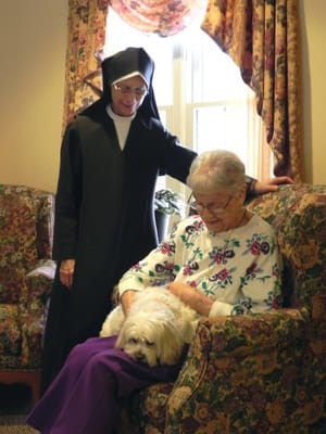 A nun and a resident in a common area with a dog
