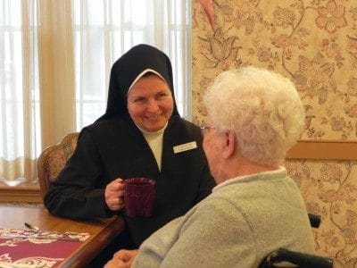 A staff member engaging with a resident in a cozy interior setting