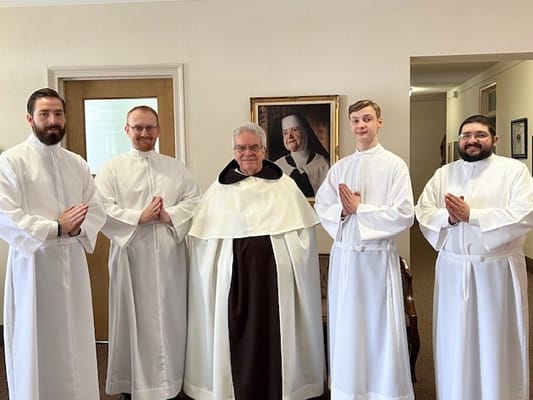 Group of individuals in white robes inside the facility