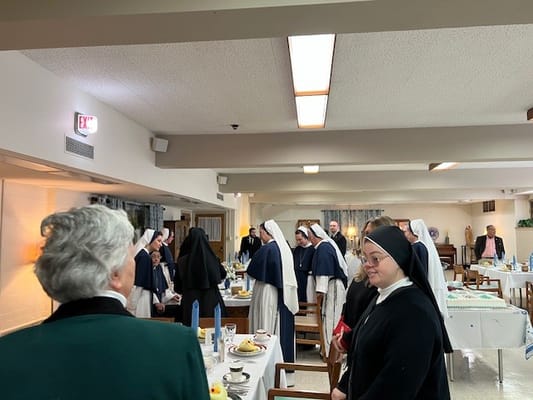 Residents and staff gathered in a dining area with meal setting