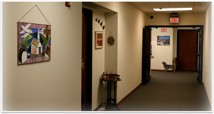 A hallway with a stained glass artwork and a dog.