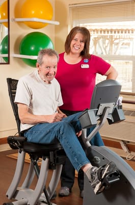 A resident using exercise equipment with staff assistance
