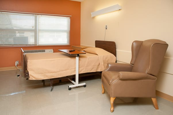 A private resident room with a bed and chair