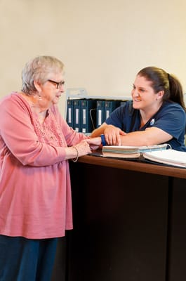 Staff member assisting a resident at the reception desk