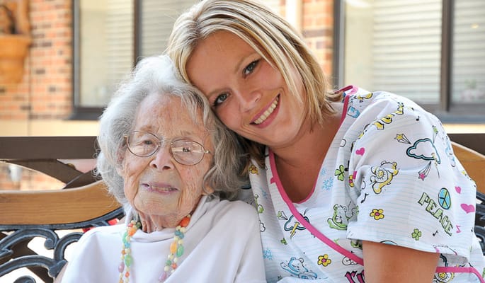 A caregiver smiling with a resident outdoors