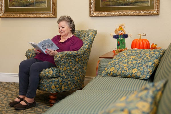 Resident reading a magazine in a cozy lounge chair