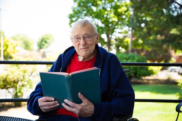 A resident reading a book in a garden area