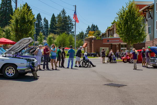 Residents and guests enjoying a car show in the facility parking lot