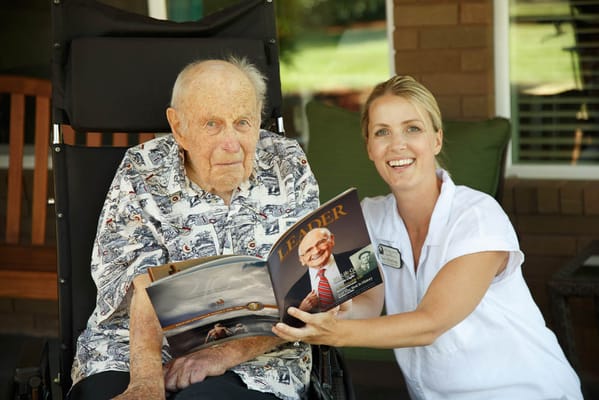 Senior resident enjoying a magazine with staff