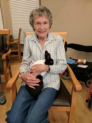 Resident smiling while holding a rabbit in a common area