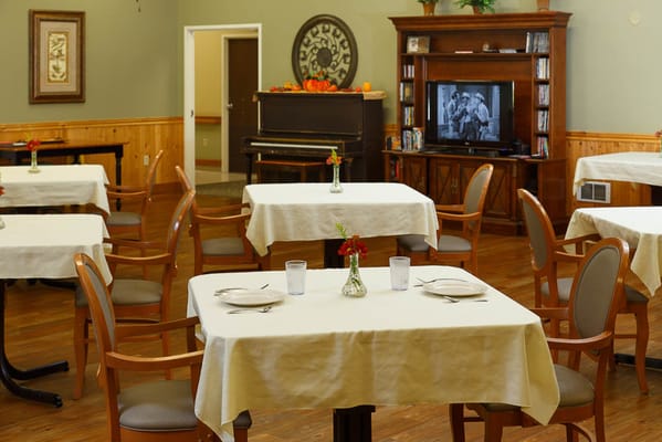 Dining room set for a meal with a piano in the background