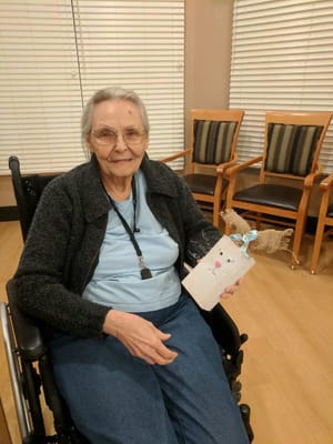 An elderly woman in a wheelchair holding a decorative item