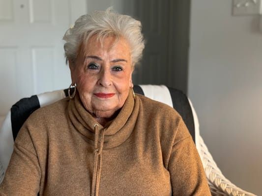 A senior woman smiling in a cozy chair