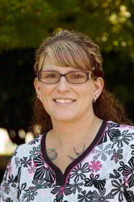 Staff member smiling in a healthcare uniform