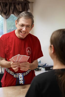 Resident playing cards with staff in a cozy interior