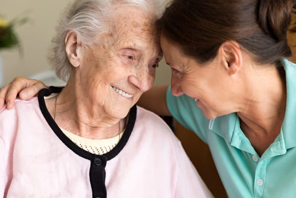 A caregiver smiling with a resident indoors