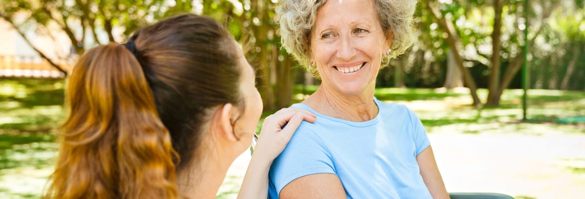 A caregiver smiling at a senior resident outdoors