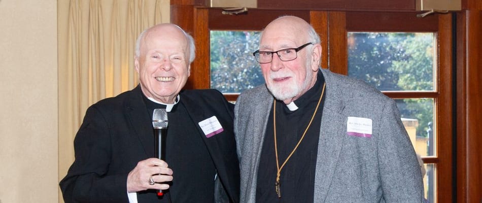 Two elderly men smiling and chatting in a common area