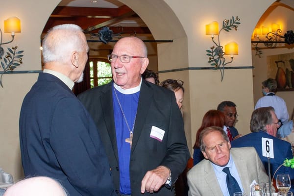 Two men conversing at a formal event indoors
