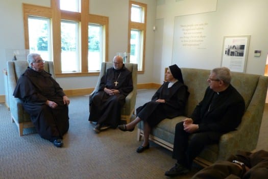 Four individuals engaged in conversation in a common area