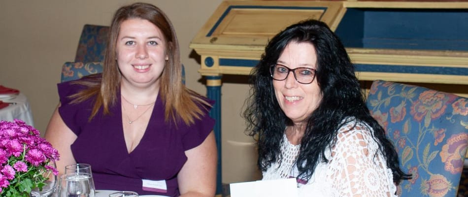 Two staff members smiling at a dining event
