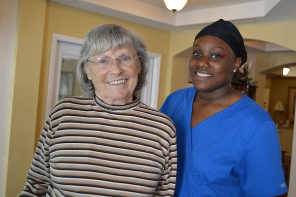 A resident smiling with a staff member in a common area