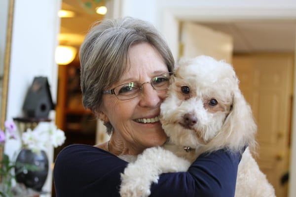 A resident joyfully holding a small dog indoors