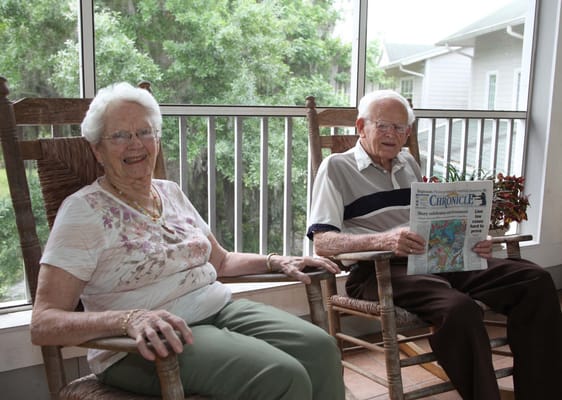 Two residents enjoying rocking chairs on a porch
