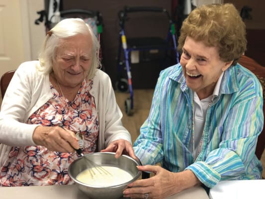 Two residents sharing a joyful moment while cooking