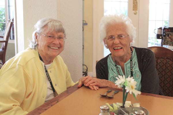 Two senior women smiling together at a table