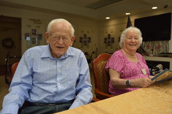Two smiling residents sitting at a table in a common area