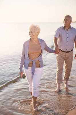 Senior couple walking along the beach at sunset