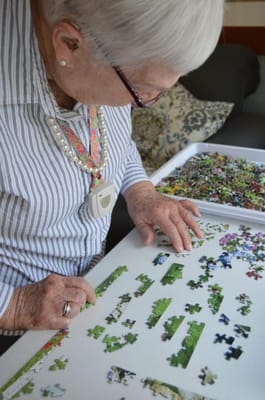 Resident assembling a puzzle in an activity area
