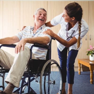 Staff assisting a smiling resident in a common area