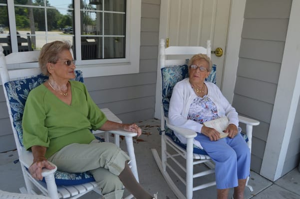 Two elderly women sitting on rocking chairs outdoors