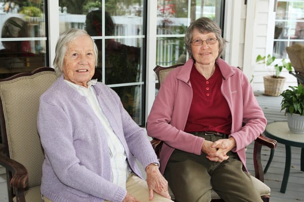 Two residents smiling on a porch