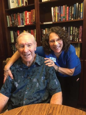 A resident and staff member smiling together in a cozy interior setting