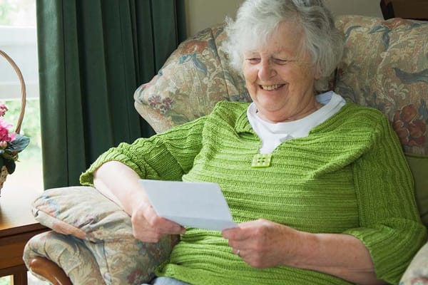 Senior resident enjoying a letter in a cozy chair