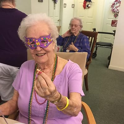Residents enjoying a festive activity with masks and beads