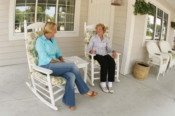 Two women enjoying time together on a porch rocking chair
